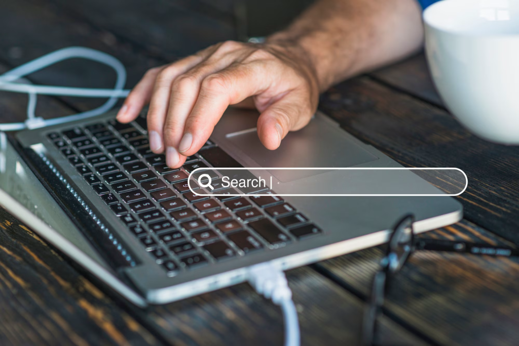 Man's hands on laptop keyboard with search bar